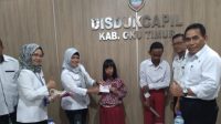 Plt. Sekdin Dukcapil OKU Timur, Endang Wahyuni, S.IP memberikan KIA kepada siswa SLB.